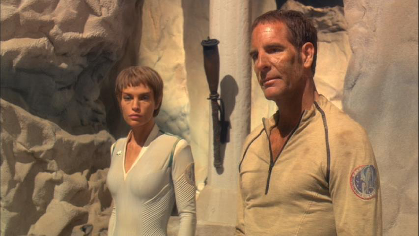 Archer (Scott Bakula) and T’Pol (Jolene Blalock) stand outside a stone wall. They are grimy, covered in dirt and sweat.