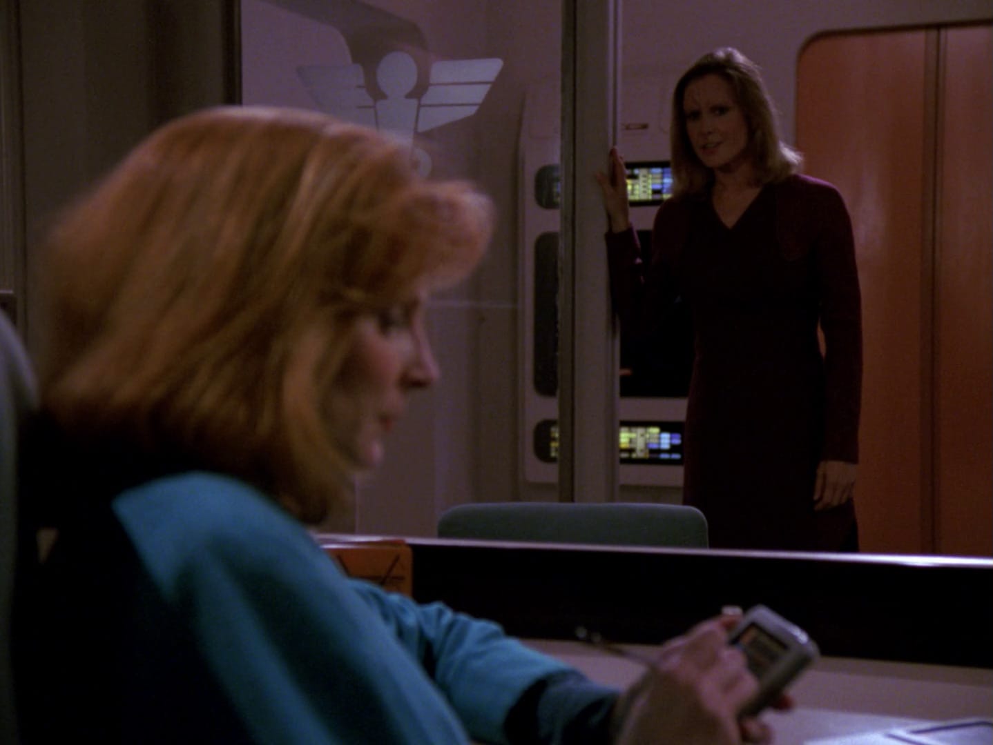 Dr. Crusher sits at her desk writing a report on her Padd. She doesn't look up as Odan's female host speaks from the doorway.